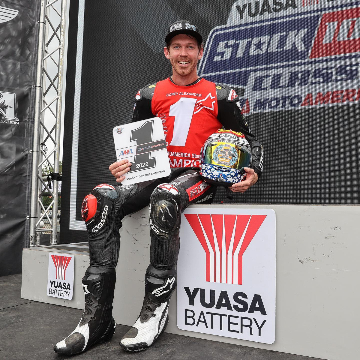 MotoAmerica Yuasa Battery Stock 1000 Champion on podium with trophy plaque