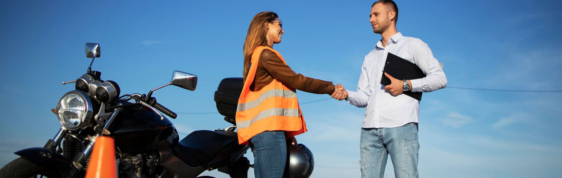 Woman thanks motorcycle safety instructor by shaking his hand.