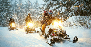 Group of snowmobilers on a trail while powder snow falls.