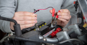 Person attaching a battery tester to their battery.
