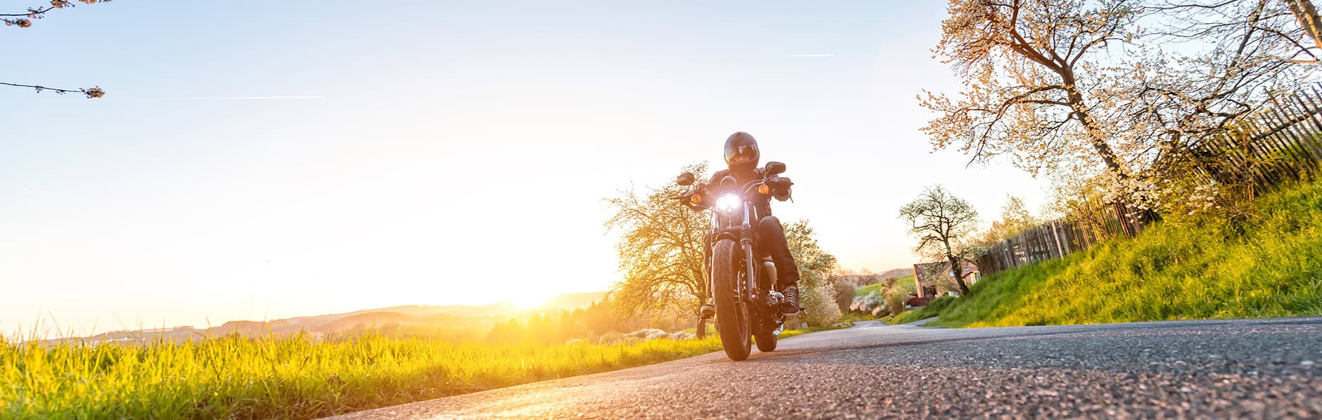 Rider takes bike out after getting it ready for spring, sun rising in the background.