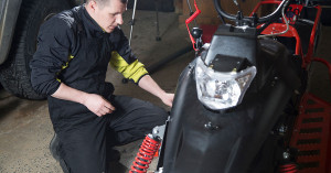 Snowmobiler checks his battery before spring storage. 