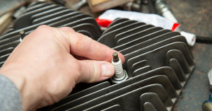 Man adjusts a sparkplug on a snowmobile.