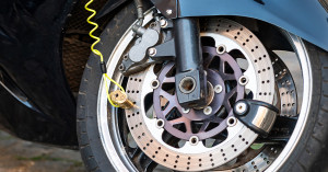 Motorcycle theft preventing rotor lock pictured on a bike wheel with a yellow cable.
